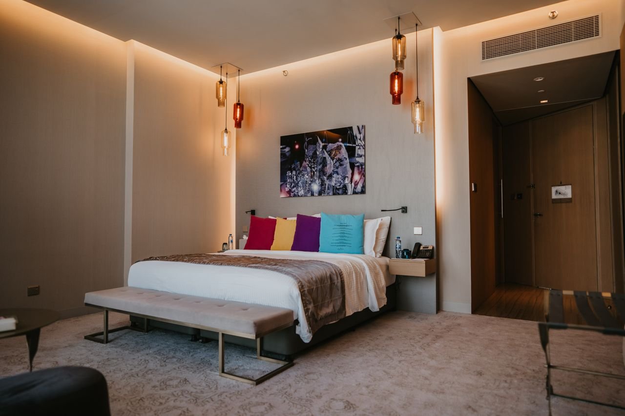 Spacious modern bedroom with colorful pillows and elegant decor in a luxury Dubai hotel.